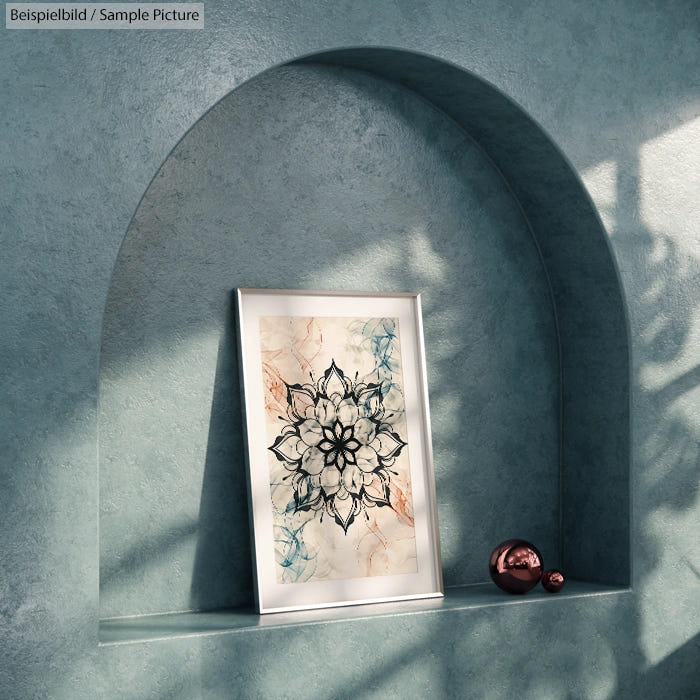 Framed mandala art on arched shelf with subtle shadows and metallic decor ball, set against textured turquoise wall.