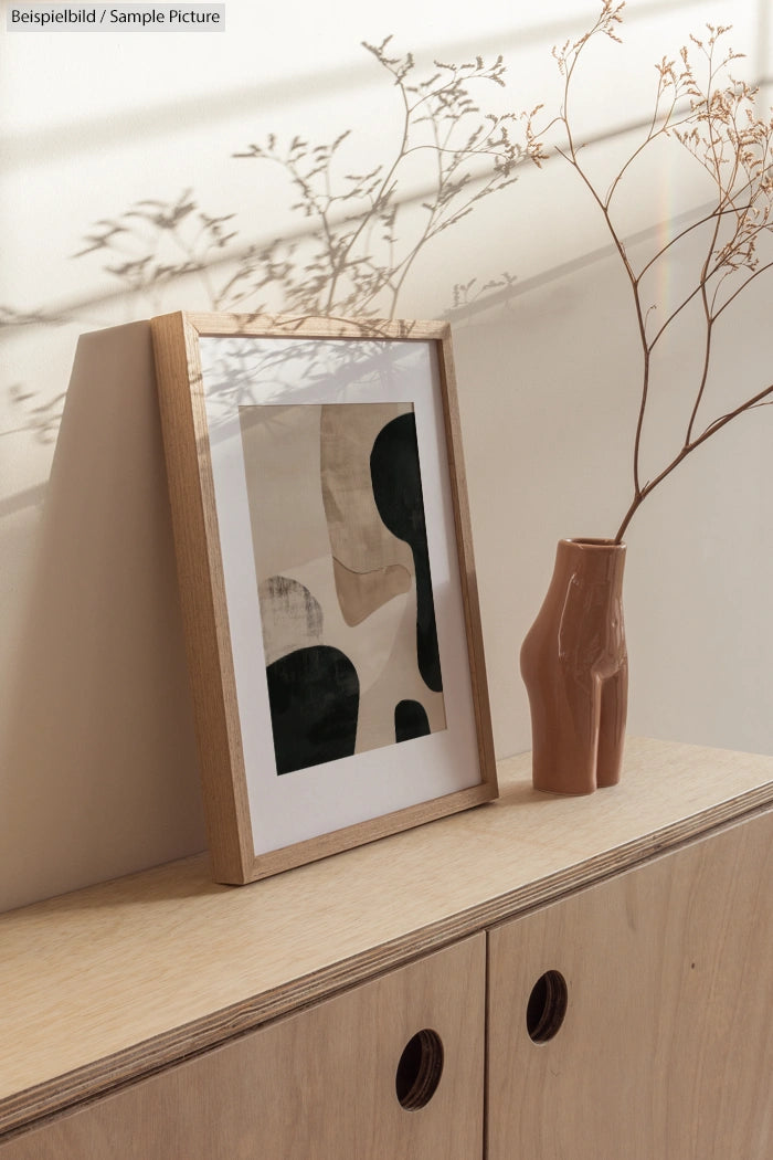 Minimalist artwork on a wooden shelf with a vase and dried branches casting shadows on the wall.