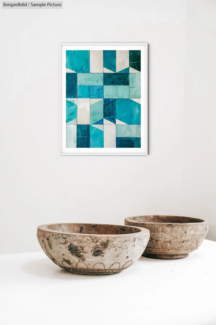 Framed geometric abstract painting with blue and green patterns above two rustic wooden bowls on a white background.