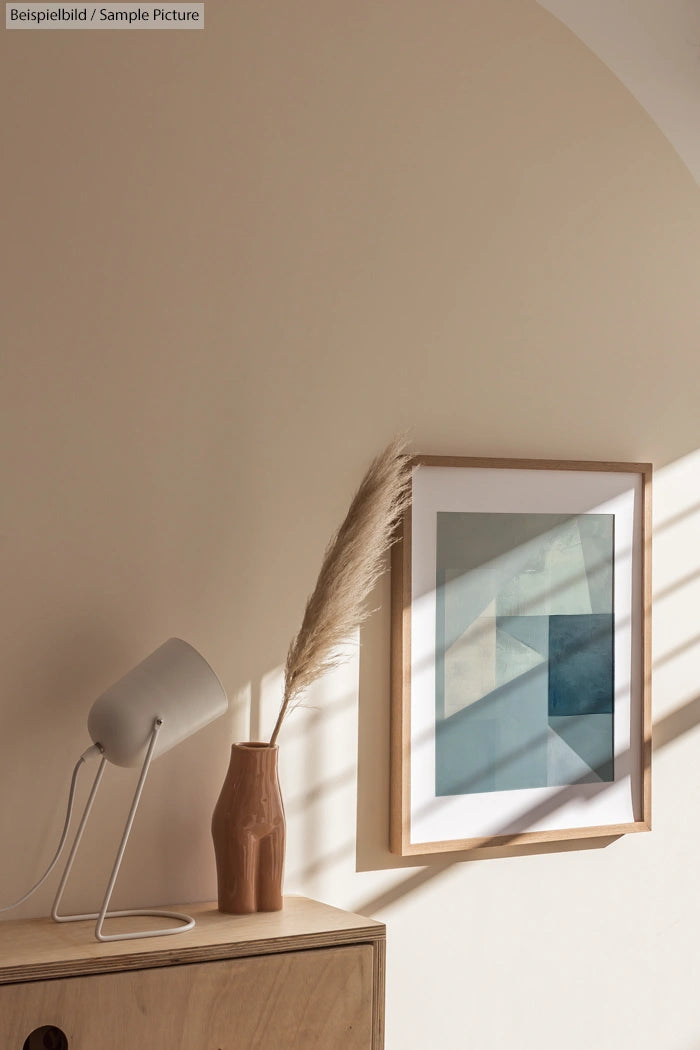 Minimalist interior with lamp, decorative vase, and framed abstract painting on a wooden side table.