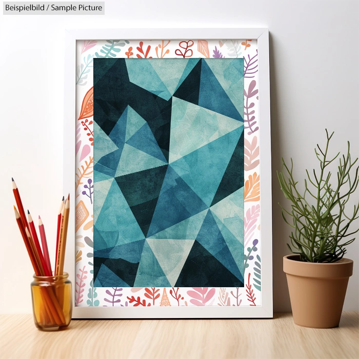 Framed abstract painting with blue geometric shapes, surrounded by colored pencil holder and small potted plant.