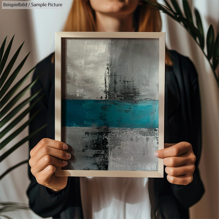 Person holding abstract painting with silver, black, and teal horizontal stripes, flanked by palm leaves.