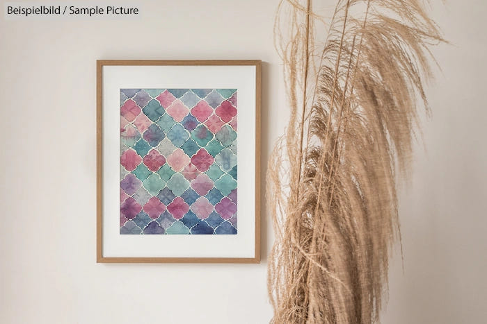 Framed geometric watercolor art on wall beside decorative pampas grass.