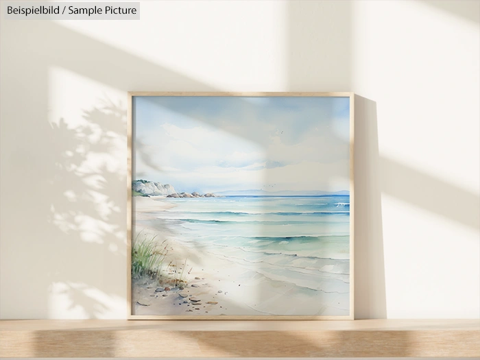 Framed beach watercolor painting on sunlit wall, featuring shoreline and gentle waves.