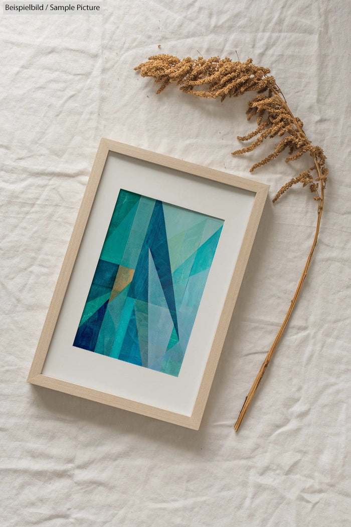 Framed abstract artwork with blue and green geometric shapes on a textured white surface with dried grass.