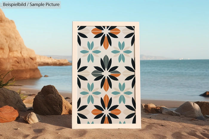 Geometric floral pattern artwork displayed on a beach with rocks and sea in the background.