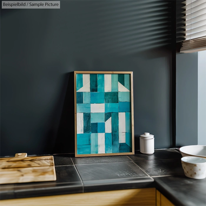 Geometric abstract painting with shades of blue and white in a modern kitchen setting with dark walls.