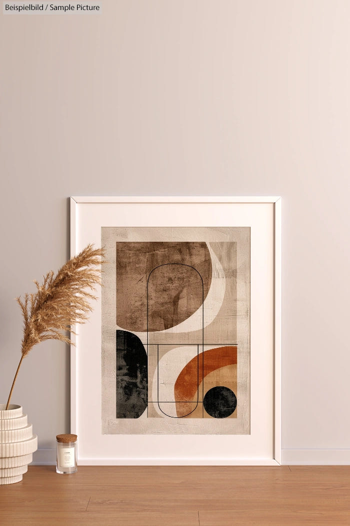 Abstract art print with geometric shapes in neutral tones, framed and displayed on a wooden floor with decor.