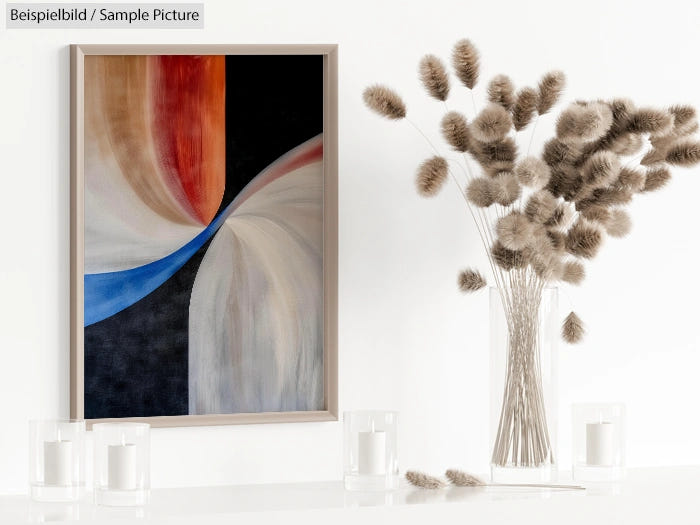 Abstract painting with earthy tones next to a vase with fluffy beige decorative plants on a white counter.