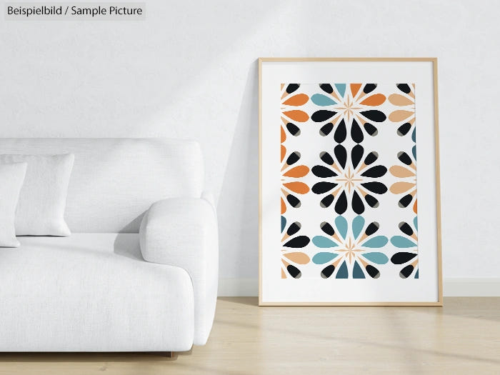 Framed abstract art with geometric floral pattern in black, orange, and teal, displayed next to a white sofa.