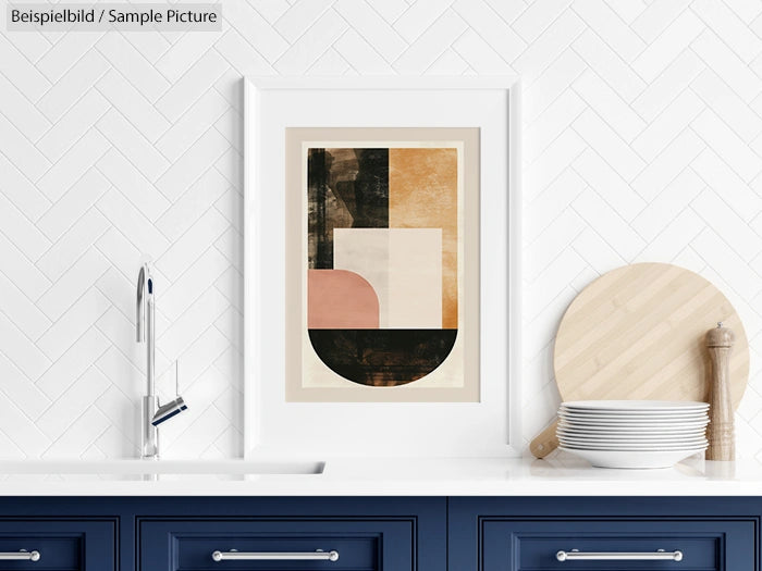 Abstract geometric art in white frame above navy kitchen cabinets with dishes and wooden board on counter.