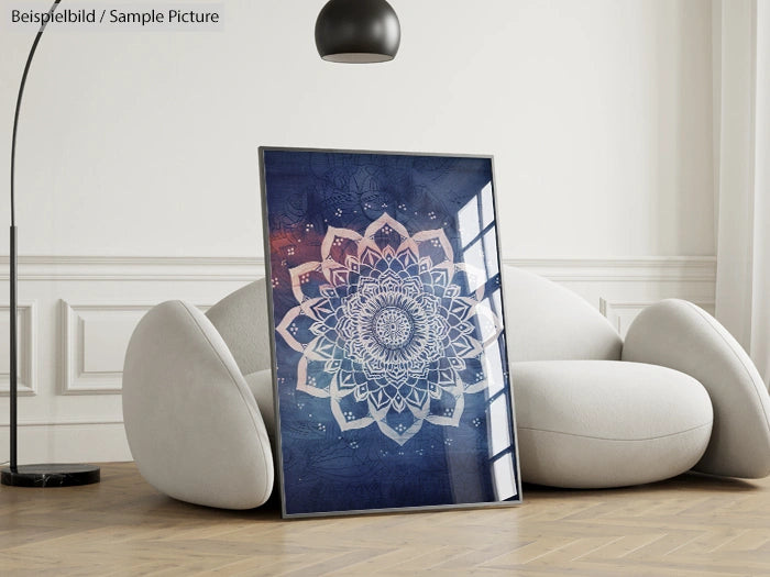 Framed mandala art with intricate patterns in blue tones, leaning against a rounded modern sofa in a minimalist room.