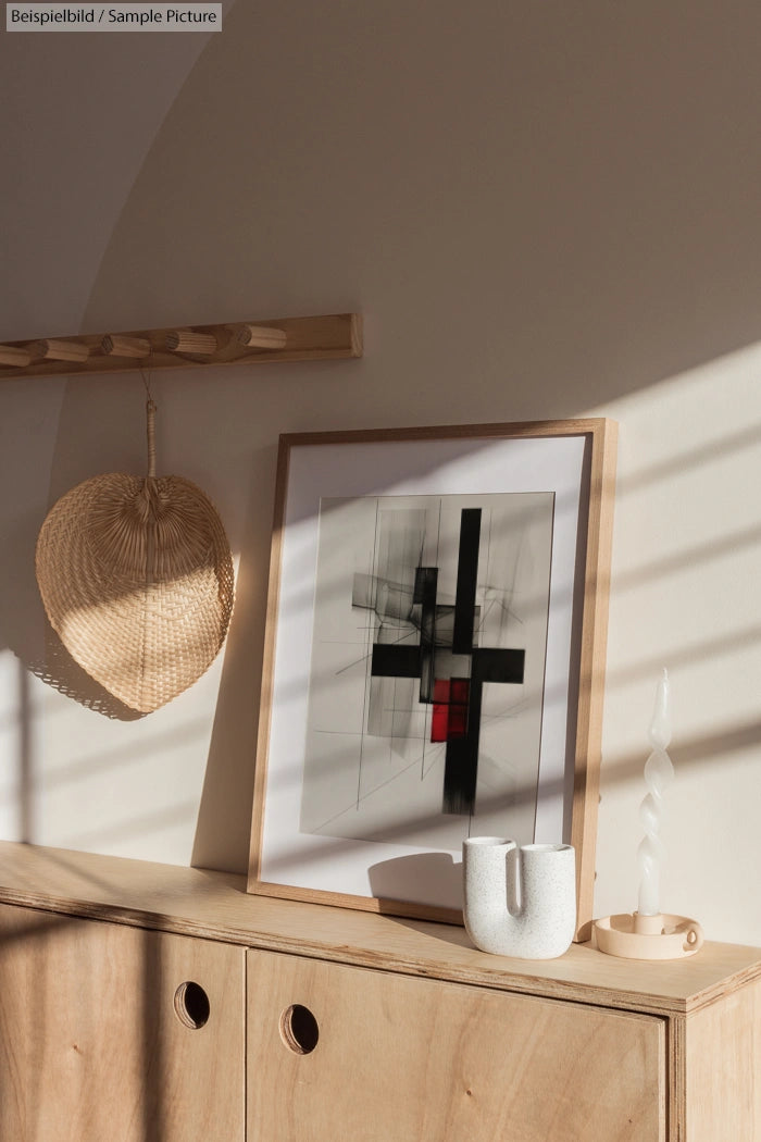 Minimalist interior with abstract artwork, ceramic vase, and candle holder on a wooden cabinet.