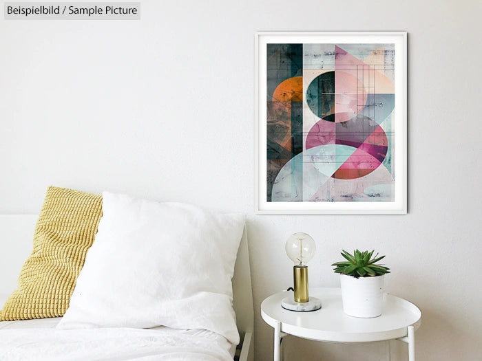 Modern abstract art in geometric shapes framed on a white wall above a cozy bed with yellow pillow and bedside table.