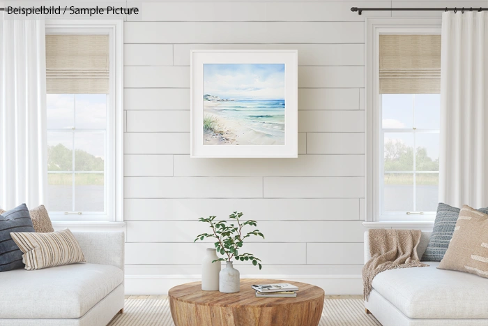 Cozy living room with white decor, wooden table, and seascape painting on a shiplap wall between bright windows.