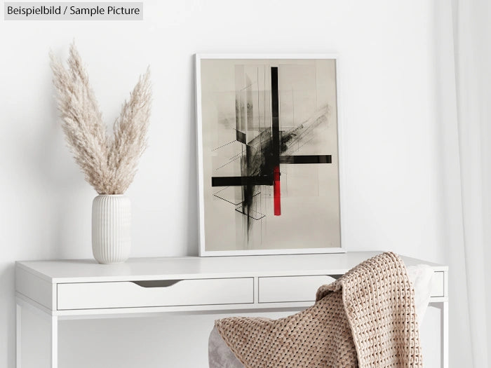 Modern abstract artwork on wall above a white desk with a vase and plant, covered by a textured throw blanket.