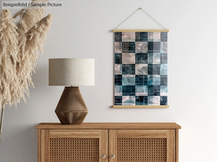 Wooden sideboard with lamp and abstract checkered wall art on white wall.