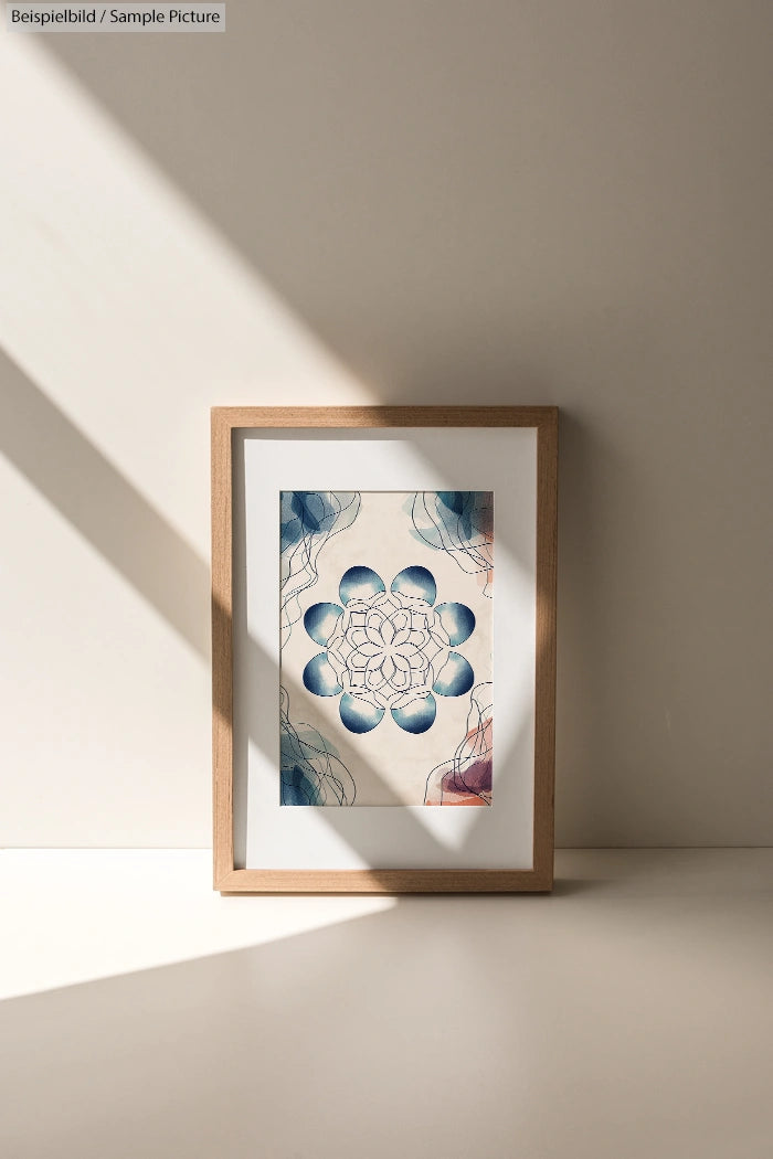 Framed abstract artwork with geometric blue and white pattern, illuminated by soft sunlight and shadows on a beige background.