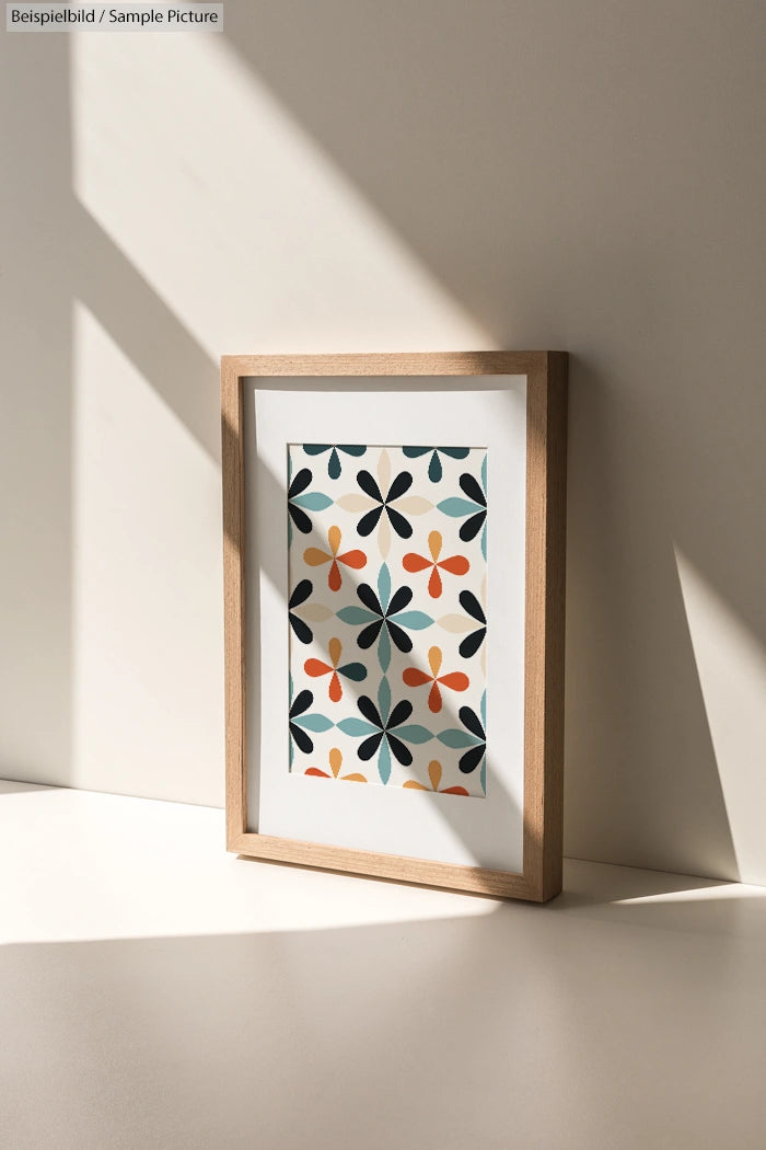 Framed art print with a colorful geometric floral pattern, casting shadows in soft natural light.