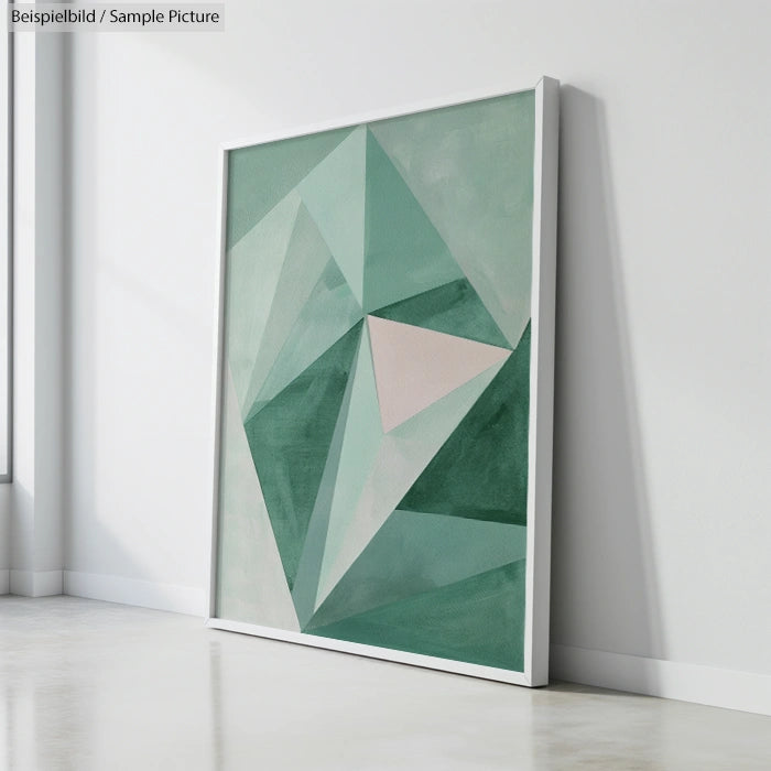 Framed abstract geometric painting with green and beige shapes leaning against a white wall.