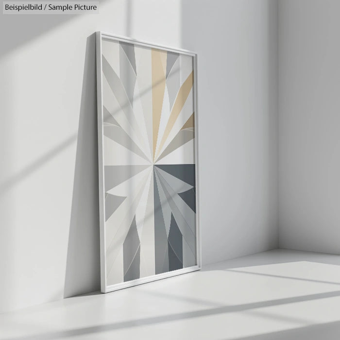 Framed abstract artwork with geometric patterns in neutral tones, leaning against a sunlit wall in a modern space.