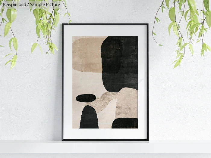 Framed abstract art print with black, beige, and textured shapes hanging on a white wall, surrounded by hanging plants.