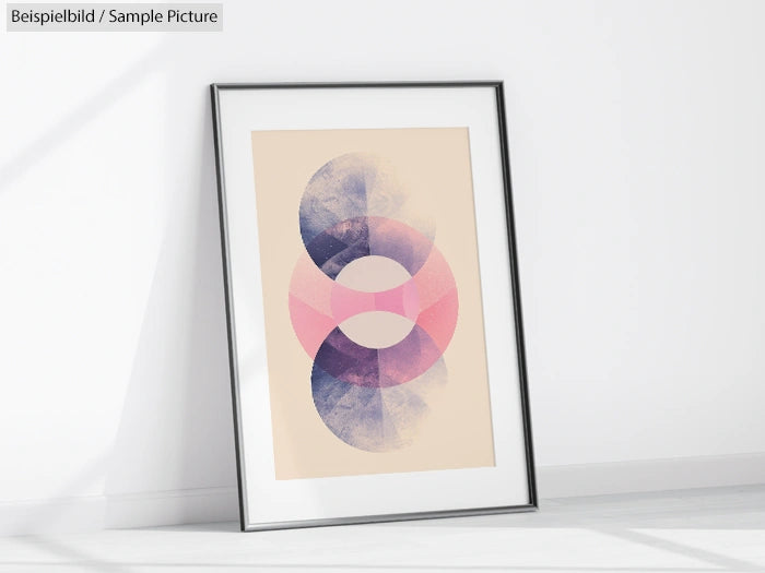 Minimalist abstract art print with overlapping blue and pink circular shapes in a black frame on a white wall.