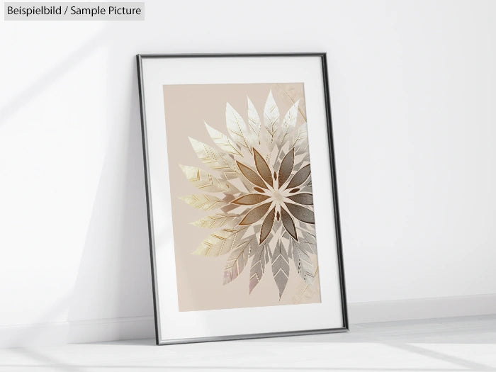 Framed geometric artwork with metallic leaf pattern leaning against a white wall in bright light.