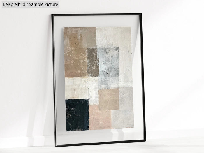 Framed abstract painting with neutral geometric shapes, leaning against a white wall.