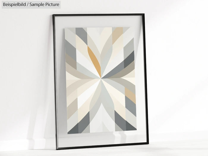 Framed geometric art print with gray, beige, and white triangular pattern, leaning against a white wall.