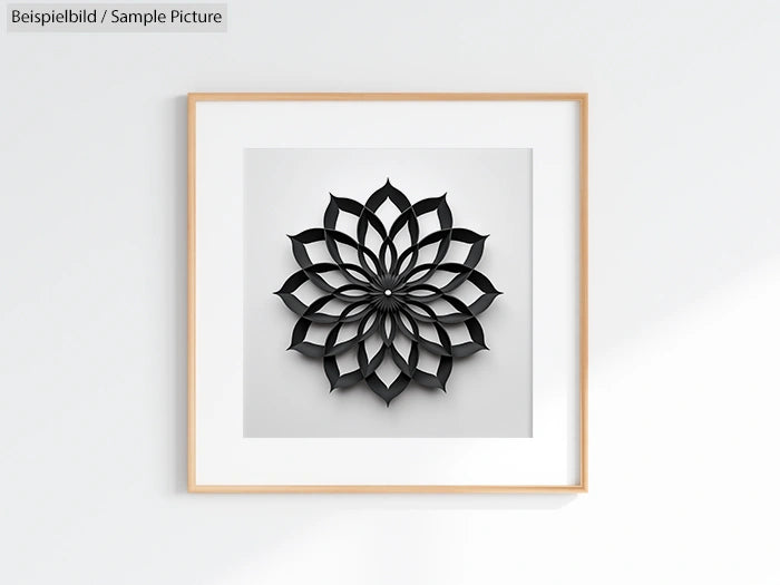 Minimalist artwork with black geometric flower pattern in wooden frame on white wall.