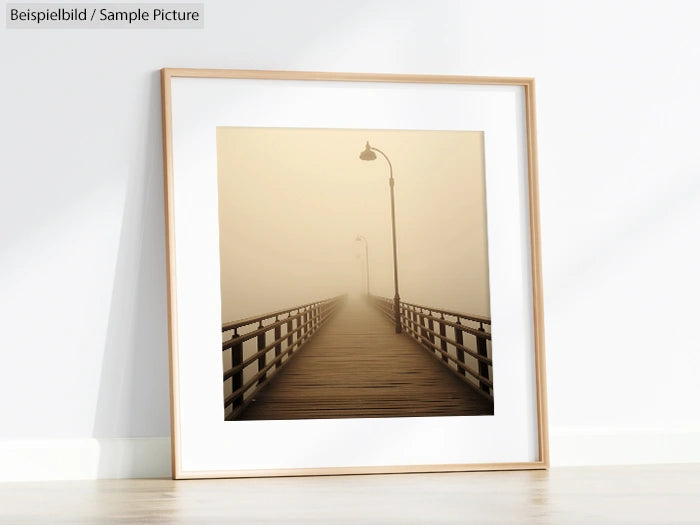 Framed photo of a foggy pier extending into the distance, with a sepia tone, displayed on a white wall.