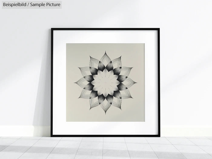 Minimalist framed artwork of a symmetrical floral design on a light gray background, displayed on floor against wall.