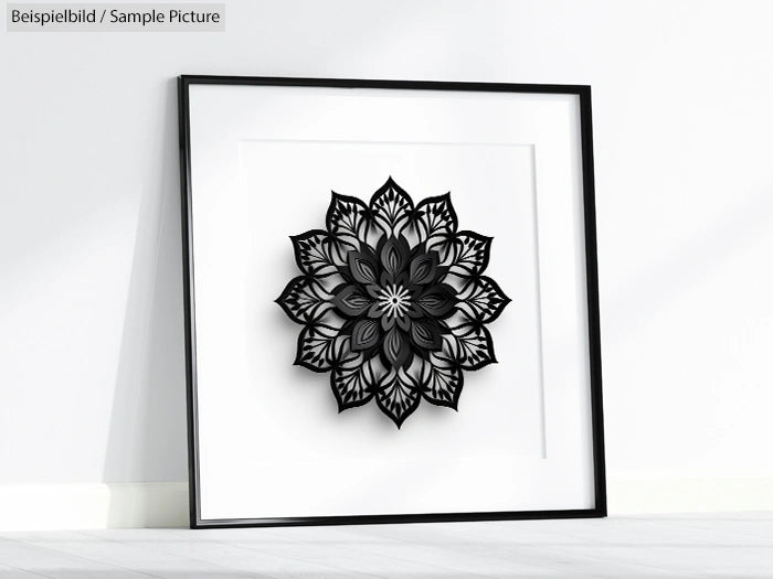 Framed black and white mandala artwork leaning against a white wall on a floor.