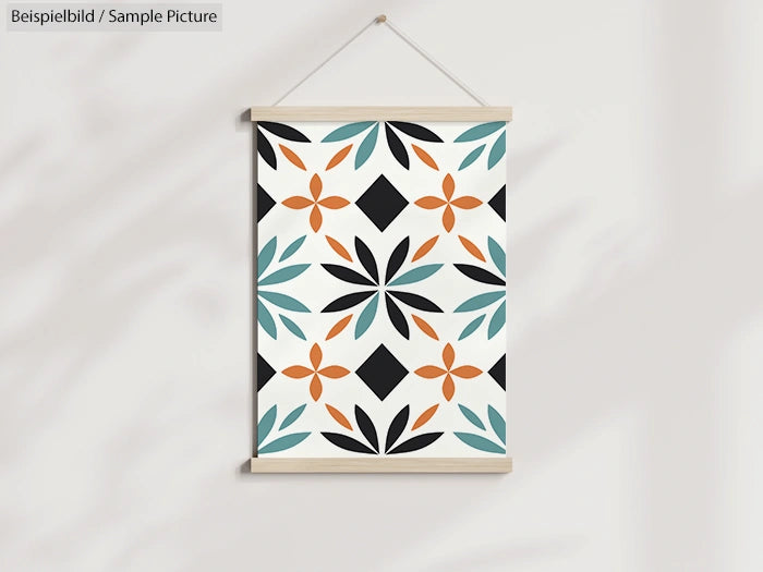 Geometric wall art with orange, black, and teal floral and diamond pattern hanging on a light wall.