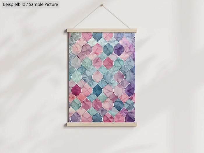 Geometric watercolor poster with pink, blue, and purple hues, hung on a wall with a wooden frame.