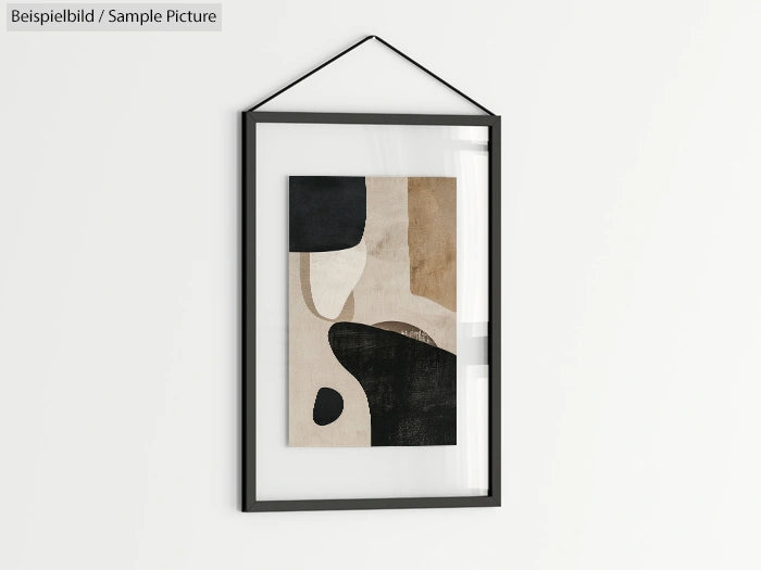 Framed abstract artwork in beige, black, and white tones on a white wall.