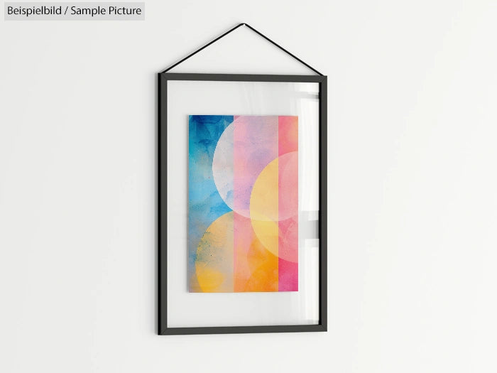 Framed abstract art print with colorful overlapping circles in blue, pink, and yellow on white wall.