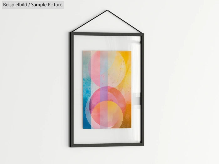 Framed abstract art with overlapping colorful circles on a light background, hanging on a white wall.