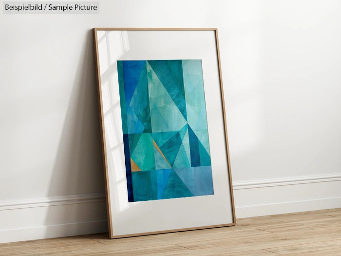 Framed abstract geometric painting with blue and turquoise triangles against a white wall on wooden floor.