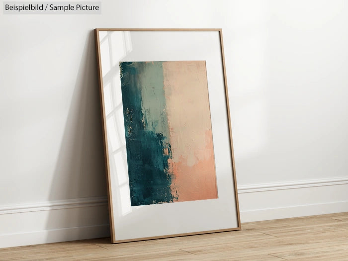 Framed abstract painting with turquoise and coral colors leaning against a white wall on a wooden floor.