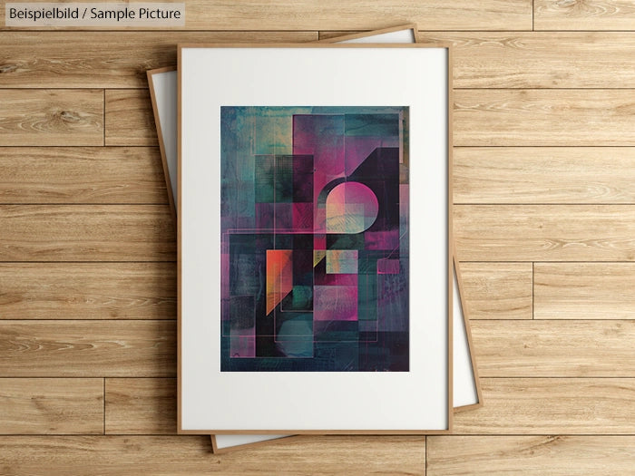 Framed abstract painting with geometric shapes in pink, blue, and green hues on a wooden floor background.