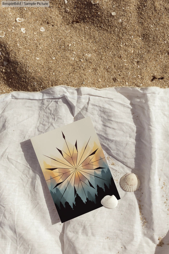 Postcard with geometric compass design on sandy beach next to seashells, placed on a white cloth.