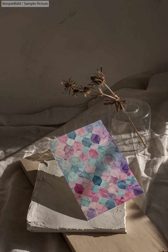 Abstract watercolor pattern on paper, styled with dried plant and glass vase on textured fabric backdrop.