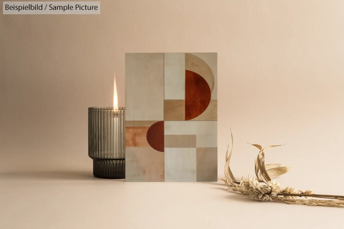 Minimalist geometric art with candle and dried flowers on neutral background.