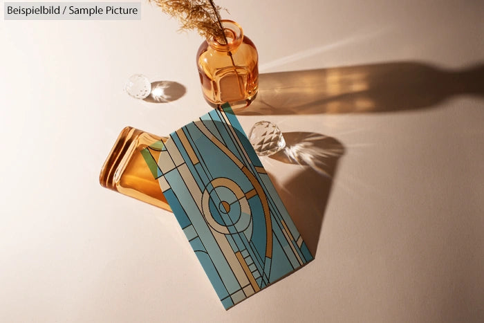 Art deco pattern in blue on table with amber glass bottle casting shadows.