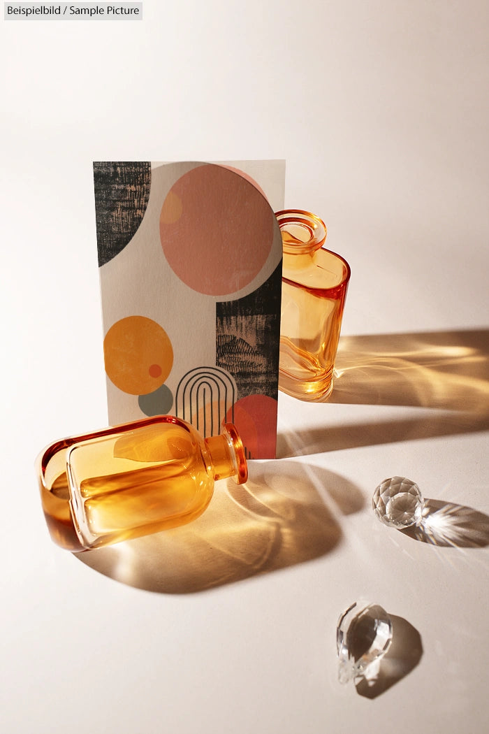 Artistic arrangement with two amber glass bottles, abstract card, and crystal spheres on a light surface.