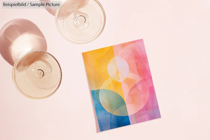 Colorful abstract geometric print beside two round glass shadows on a light background.