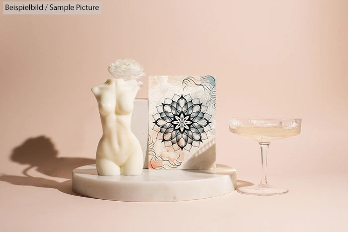 Artistic display with a floral sketch, a sculpted torso, and a champagne glass on a marble platform.