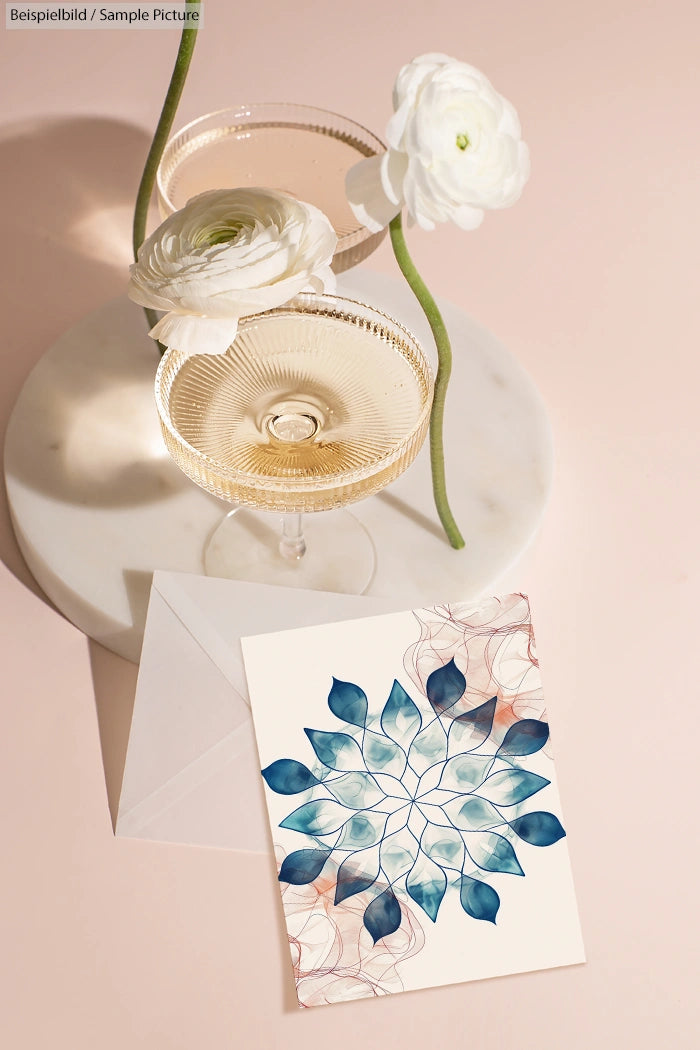 Champagne glasses with white flowers and artistic card on marble surface.